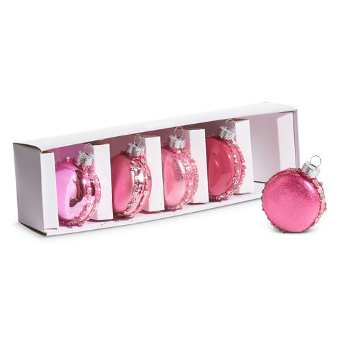 The PINK MACAROON ORNAMENTS by RAZ IMPORTS are a set of five round, shiny, pink Christmas ornaments with a glitter trim, crafted from glass. Four come in an elegant white box while one is showcased outside. These decorations perfectly capture the festive spirit and are ideal for holiday adornment.