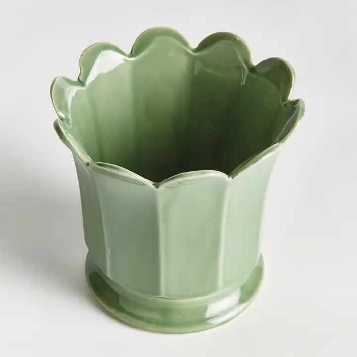 The NAPA HOME AND GARDEN Maline Footed Pot in Green, Large, features a light green ceramic finish with a scalloped, petal-like rim and a flared, rounded base. This elegant vase by NAPA HOME AND GARDEN is photographed against a plain white background.