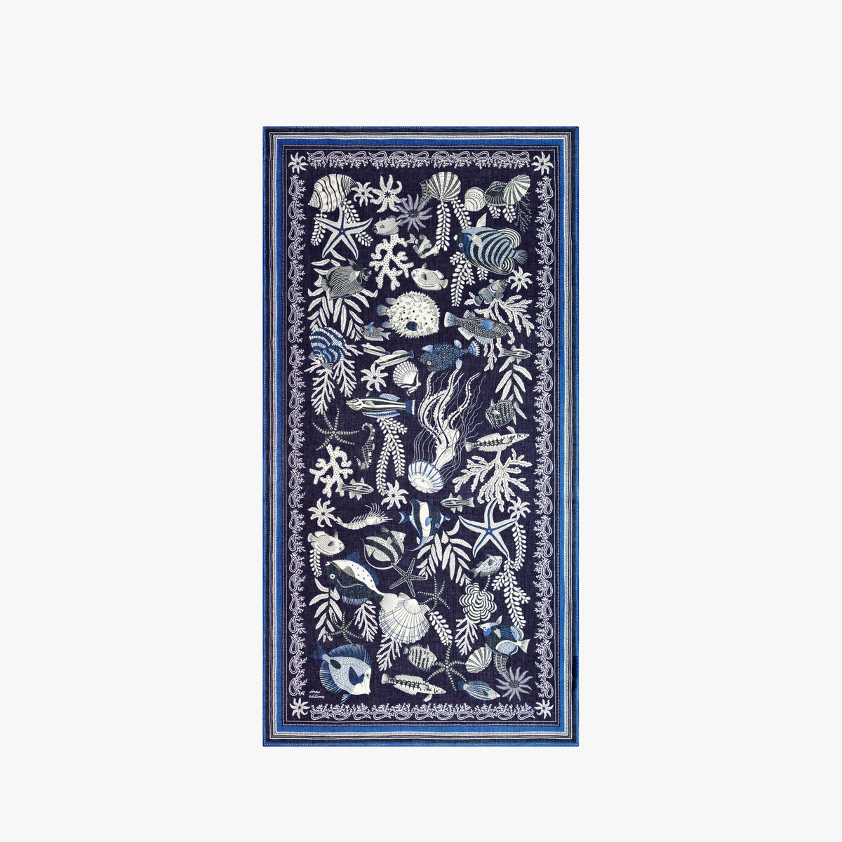 A woman faces forward, wearing a sleeveless cream and navy top with white botanical and animal motifs, accessorized with the INOUI EDITIONS - NEPTUNE SCARF IN NAVY by INOUI, draped loosely around her neck.