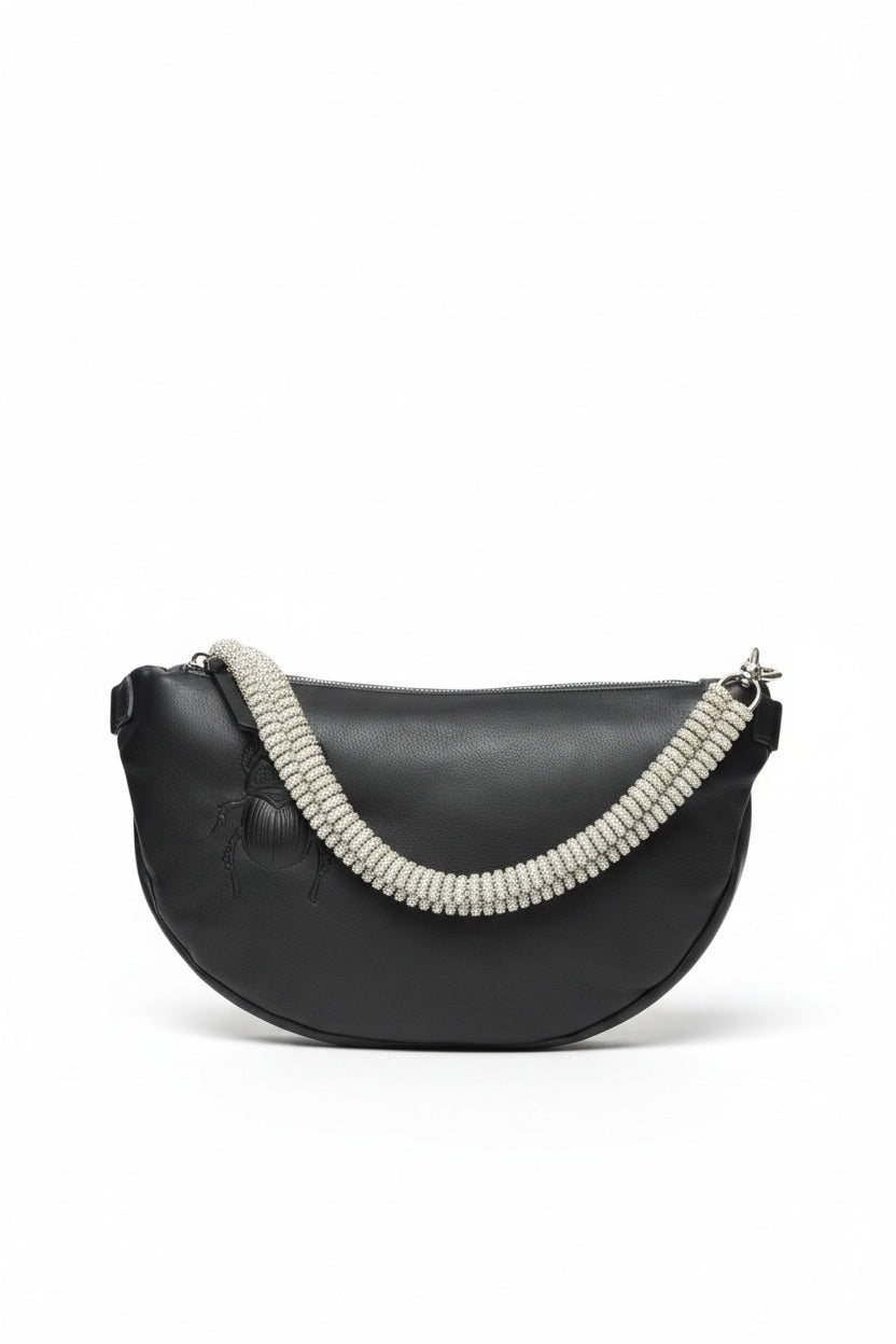 The GANRIELE FRANTZEN - SCARAB LEATHER XL BELT BAG IN BLACK WITH EXTRA CRYSTAL STRAP by GABRIELE FRANTZEN is a black leather, crescent-shaped crossbody bag featuring a long black strap and an extra decorative crystal handle, displayed against a plain white background.