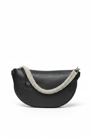 The GANRIELE FRANTZEN - SCARAB LEATHER XL BELT BAG IN BLACK WITH EXTRA CRYSTAL STRAP by GABRIELE FRANTZEN is a black leather, crescent-shaped crossbody bag featuring a long black strap and an extra decorative crystal handle, displayed against a plain white background.
