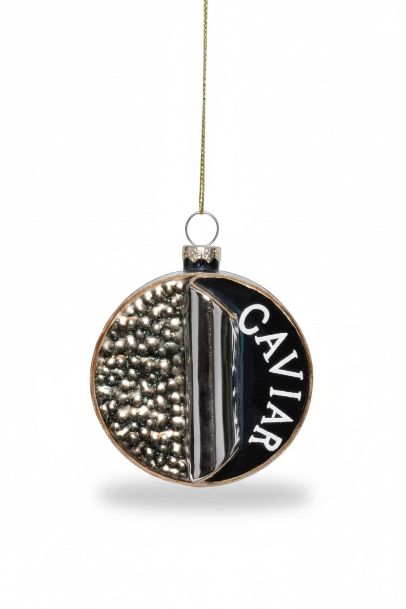 A ZODAX GLASS CAVIAR BOX ORNAMENT shaped like a 3-inch round tin with “CAVIAR” text and metallic beads, sitting in a silver serving dish next to a bowl of potato chips.