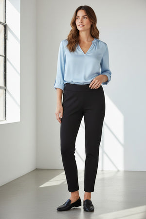 Wearing the KRAZY LARRY, INC PULL ON STRAIGHT LEG MICROFIBER PANT in white, paired with a dark patterned top and red shoes, a person poses against a white background. The image features only the lower half of their body, highlighting this chic office-ready style.
