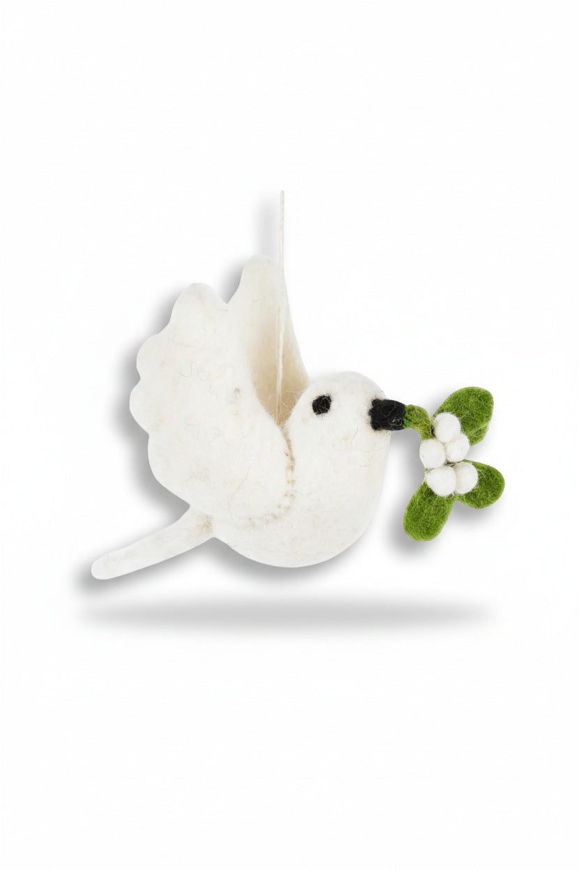 A MISTLETOE DOVE ORNAMENT by FELT SO GOOD hangs on a tree, the felt dove holding a sprig of mistletoe in its beak.