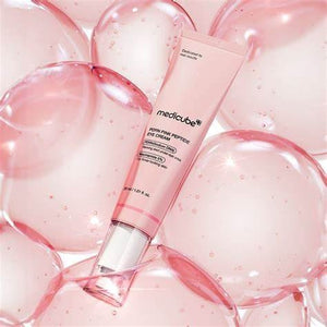 A pink tube of KOSMIC KBEAUTY SKINCARE MEDICUBE - PDRN Pink Peptide Eye Cream, 30ml, an under-eye brightening retinol eye cream, is displayed on a background of translucent pink bubbles.