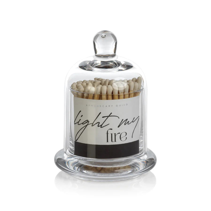 Glass cloche containing LIGHT MY FIRE matches of varying dimensions, featuring a label that reads “Apothecary Guild” and “light my fire.”.