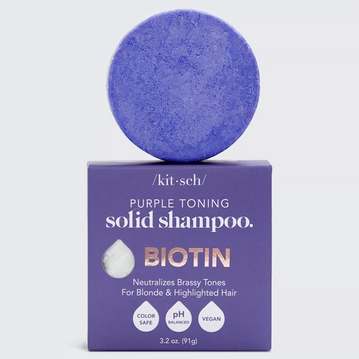 A KITSCH purple toning solid shampoo bar for blonde and highlighted hair, weighing 3.2 oz (91g), sits on its box labeled "KITSCH - Purple Toning Solid Shampoo Bar." It reduces brassiness and is color-safe, pH balanced, and vegan.