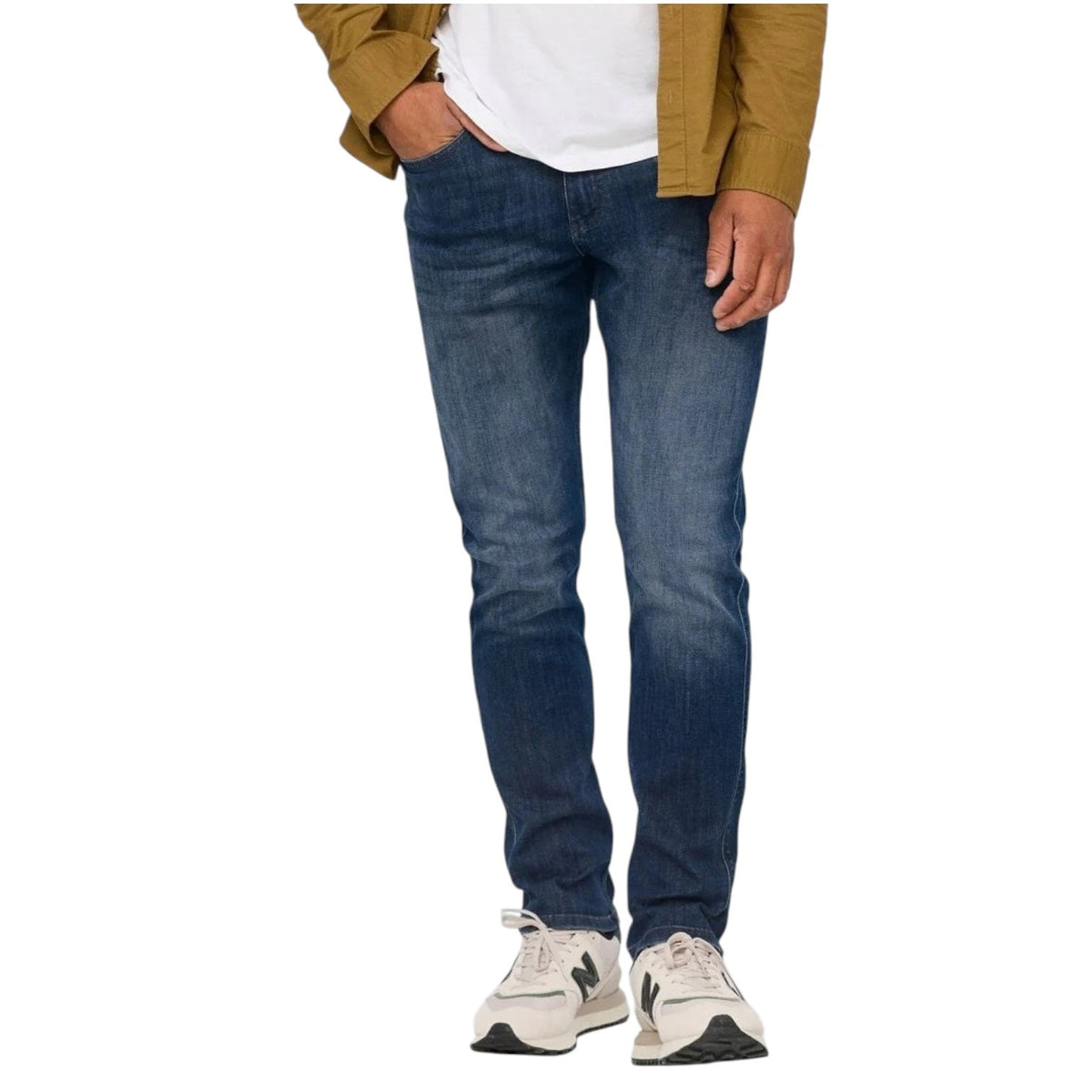 A person wearing a white t-shirt, DUER PERFORMANCE DENIM ATHLETIC TAPER PANTS IN GALATIC, and white sneakers stands facing away from the camera against a plain light background.