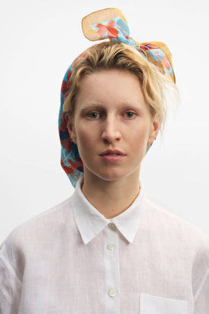 The EPICE - WARHOL BANDANA SCARF by EPICE features a purple base with a yellow floral pattern outlined in orange. It has crimped edges, an abstract Pop Art design, and vibrant hand-screen printed motifs on a plain white background.