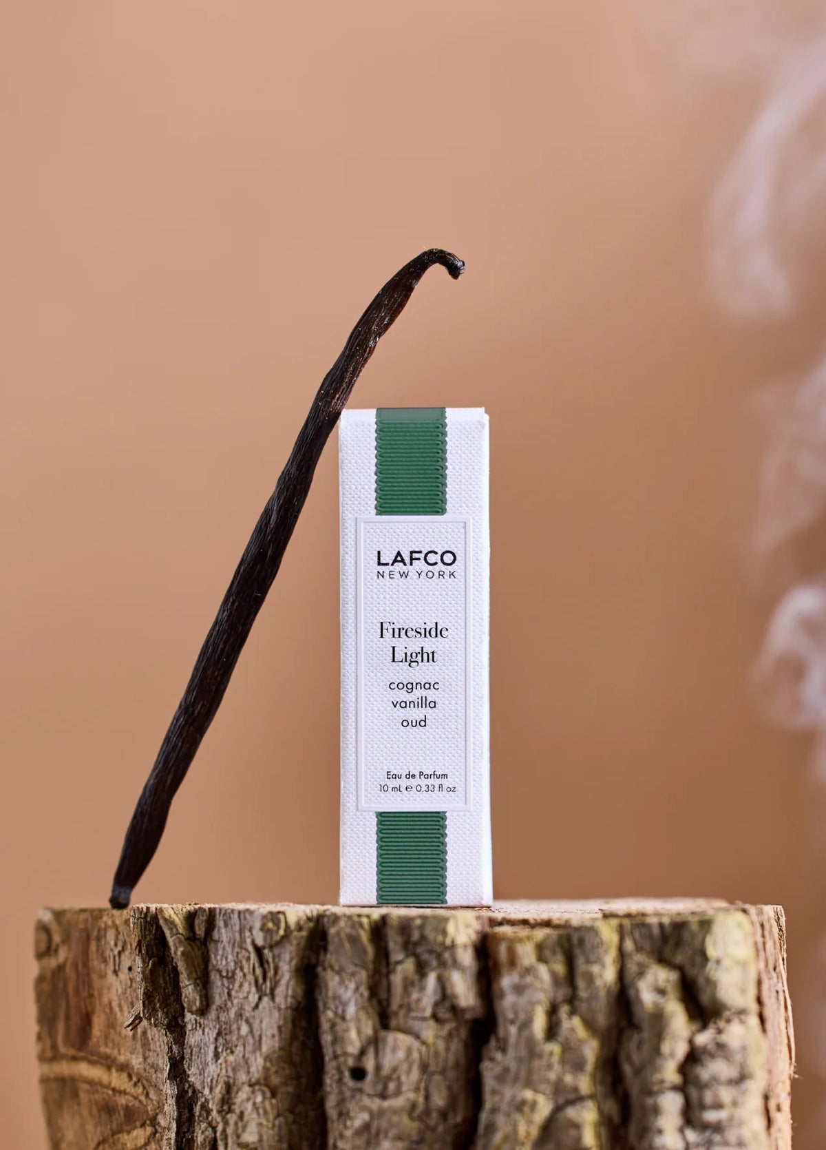 A yellow bottle of LAFCO - FINE FRAGRANCE, FIRESIDE LIGHT 10ML stands upright on a white background, featuring a marble-patterned green cap and reflecting the ambered vanilla notes of this vegan perfume.