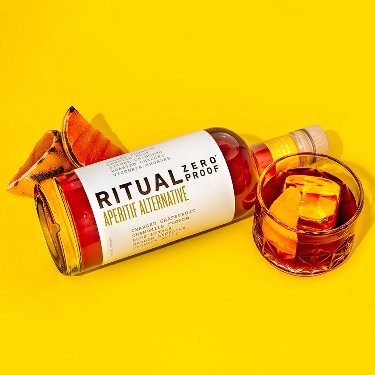 A clear glass bottle of Ritual Zero Proof Aperitif Alternative, featuring vibrant red liquid and a white label with bold black and yellow text—perfect for making a refreshing non-alcoholic spritz or Italian aperitivo.