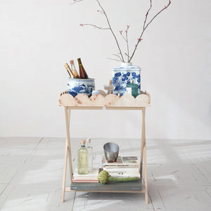 The CREATIVE COOP BURL WOOD VENEER FOLDING TABLE features crossed legs and a removable scalloped tray with a wavy rim and natural wood grain, blending charm with practical design.