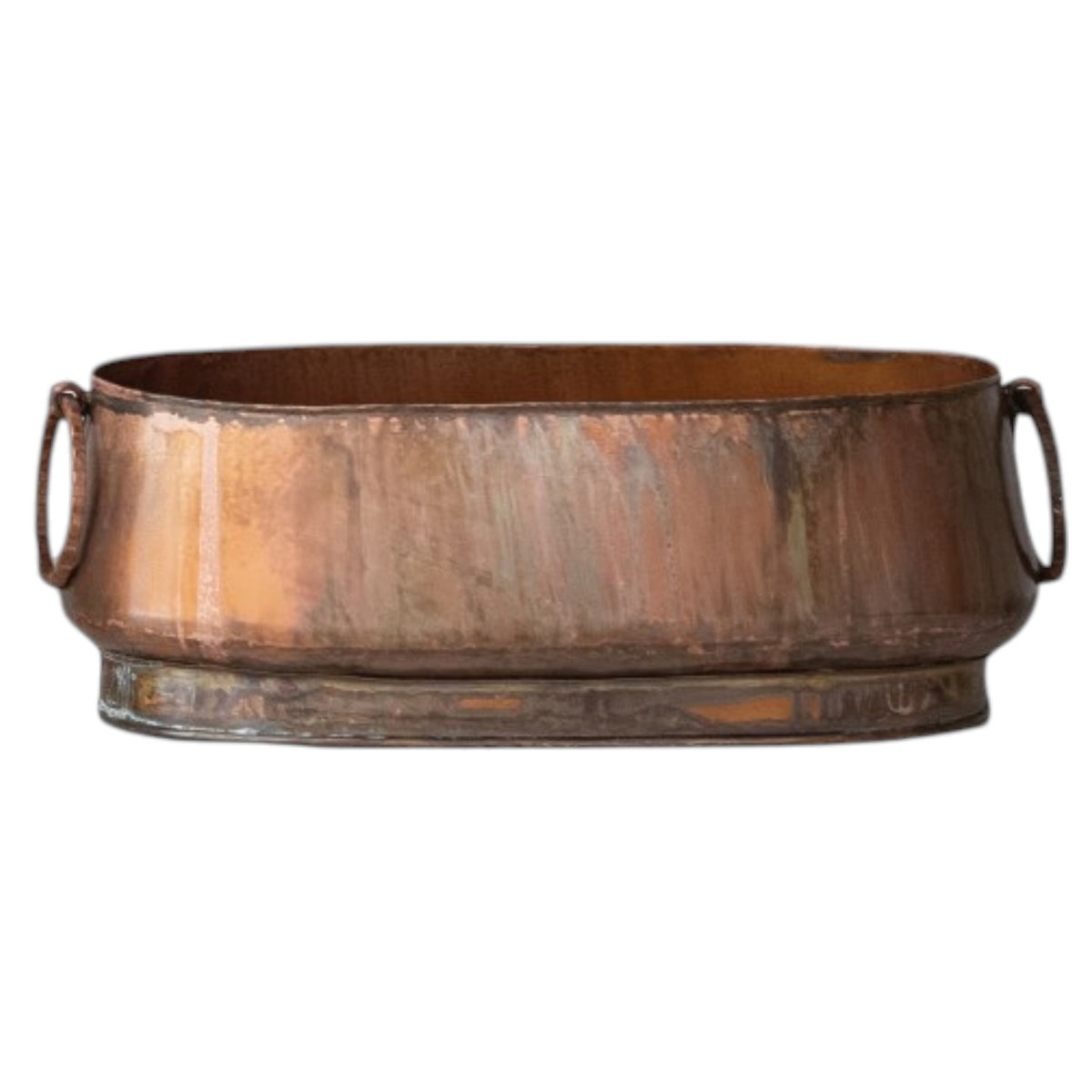 The CREATIVE COOP OVAL METAL PLANTER WITH RING HANDLES, LARGE holds books and dried plants on a light cloth next to a matching cup, set against a plain light wall for charming farmhouse décor.