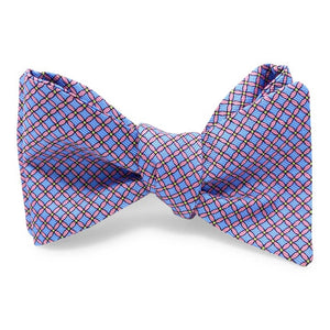 The PETER-BLAIR Cushions Silk Bow Tie in blue by BIRD DOG BAY features a self-tie, butterfly design with a red and black grid pattern. Made from printed silk, this untied bow tie shows adjustable neck sizing and pointed ends on a white background.