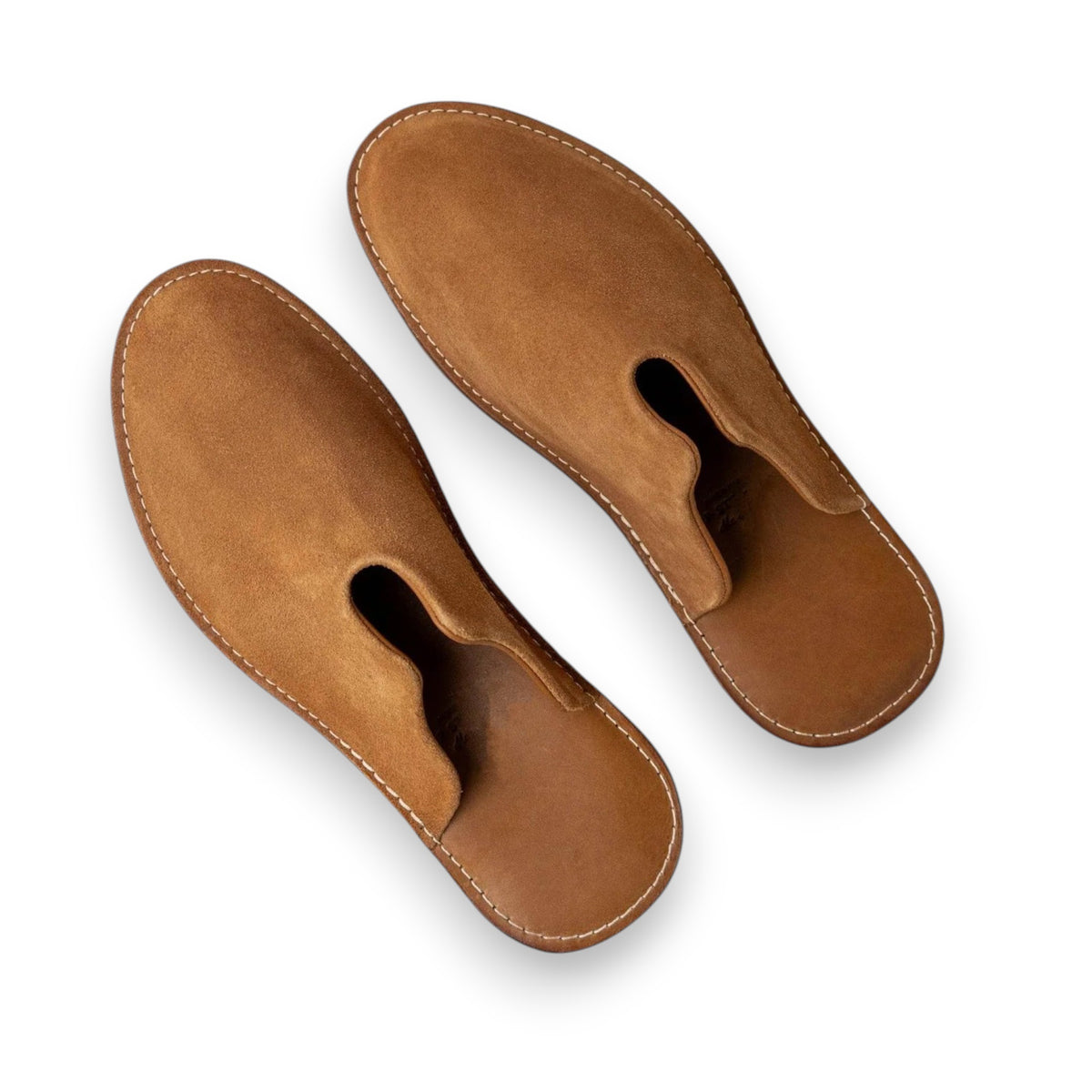 The WP STANDARD - MR GRUMPY LEATHER SLIPPER by WP STANDARD is a brown leather slipper with white stitching, cushioned heel, and unique cutout near the front opening, shown from above on a white background.
