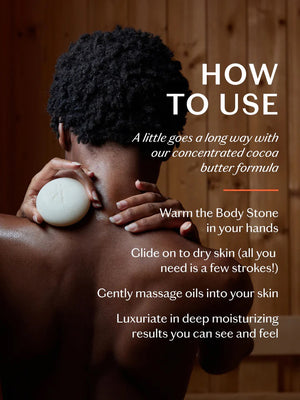 A KATE MCLEOD - DAILY STONE DEEP MOISTURIZING LOTION BAR with a wooden lid rests beside a luxurious Body Stone on beige cloth against a blue backdrop, promising daily indulgence.