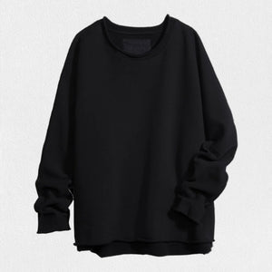 A person with long, wavy blonde hair is standing outdoors near a large tree, wearing the FRANK & EILEEN ANNA LONG-SLEEVE CAPELET in navy over a white shirt and blue pants. The background showcases green foliage and a stone path. The person is smiling and gazing to the side.