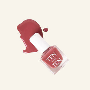 A glass bottle of TENOVERTEN - NAIL POLISH from the brand TEN OVER TEN, featuring a white cap and a dusty pink nail color. The front label displays "TEN OVER TEN" in white uppercase letters. This vegan, eight-free formula ensures both beauty and peace of mind. The background is plain and light-colored.