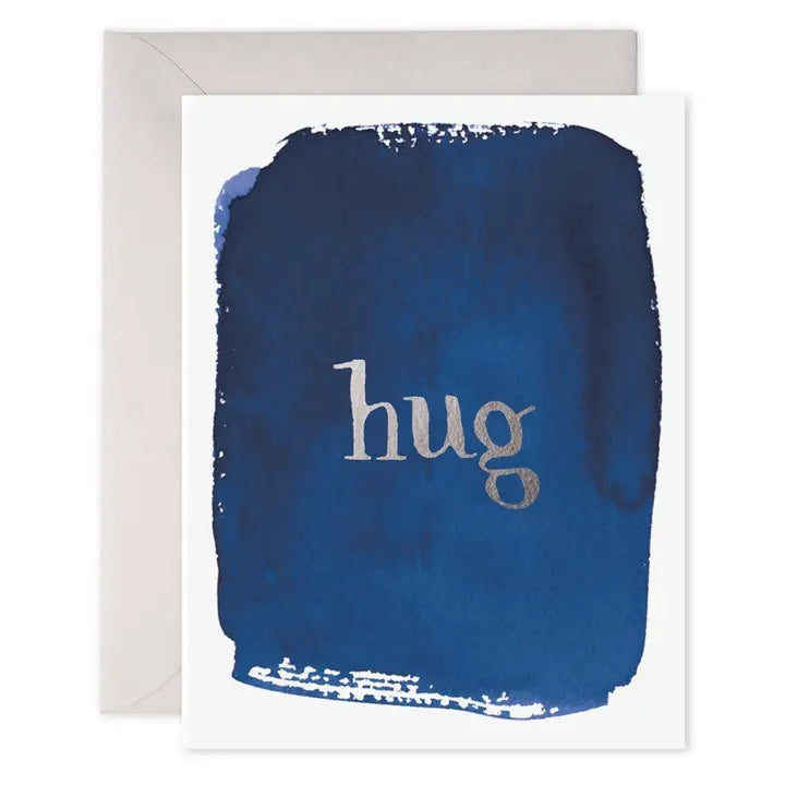 The E. FRANCES - HUG CARD by E. FRANCES PAPER features a blue watercolor design with "hug" embossed in silver on the front and comes with a light gray envelope. This comfort card is ideal for sending warm thoughts and support.