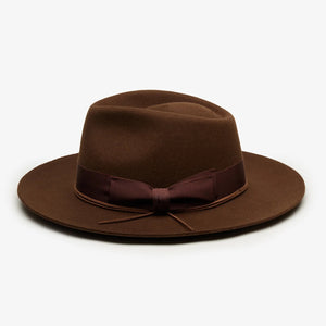 The WYETH - TEDDY HAT IN BROWN by WYETH is a vintage-inspired wide-brimmed fedora with a matching dark brown ribbon band, shown against a plain white background.