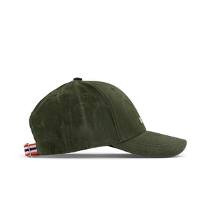 The AMUNDSEN SPORTS - WAXED COTTON CAP in navy blue is shown from the side against a plain white background, featuring a curved brim and an adjustable strap with a red, white, and black checkered norgesreima design.