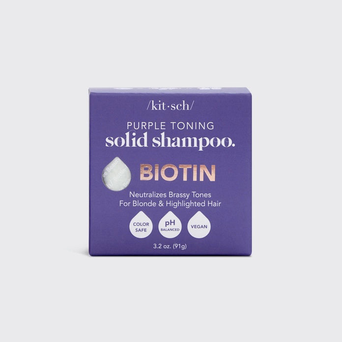 A KITSCH purple toning solid shampoo bar for blonde and highlighted hair, weighing 3.2 oz (91g), sits on its box labeled "KITSCH - Purple Toning Solid Shampoo Bar." It reduces brassiness and is color-safe, pH balanced, and vegan.