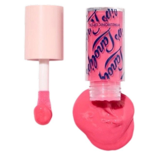 A woman with glossy pink lips holds a tube of LANOLIPS Hyaluronic Lip Oil in Raspberry near her face, looking upward with a slight smile, showcasing the non-sticky lip oil’s effortless lip hydration.
