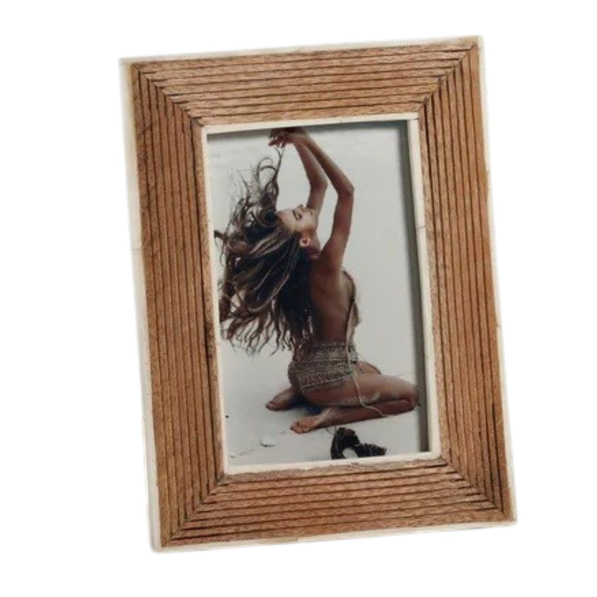 Showcase your cherished memories in the ZODAX Ribbed Mango Wood Frame with White Bone Border – 4x6. This elegant frame features an artisanal ribbed mango wood design accented by a refined white bone border, beautifully displaying a photograph of a person sitting on their knees with back exposed, arms raised, and long hair flowing against a light background.