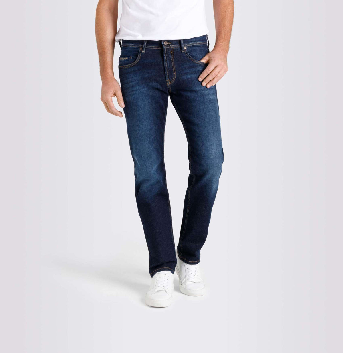 A person wearing MAC JEANS - BEN AUTHENTIC DENIM REGULAR FIT DARK VINTAGE WASH by MAC, paired with a white t-shirt and white sneakers, stands against a plain light gray background.