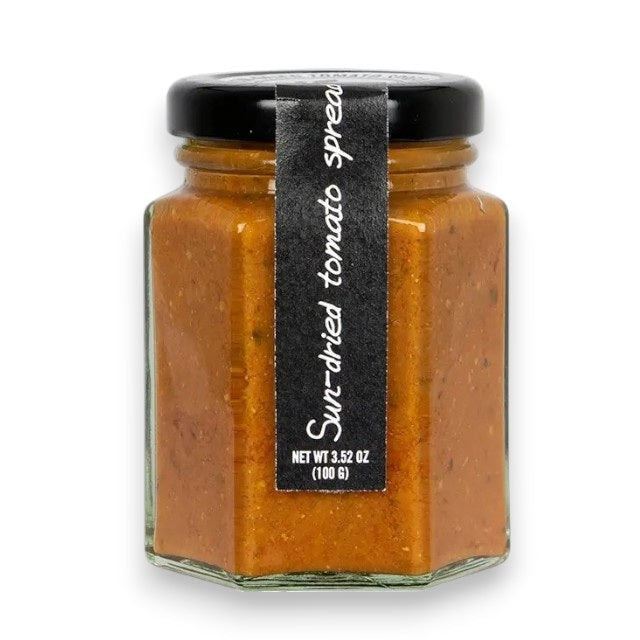 A hexagonal glass jar of RITROVO’s CASCINA ROSSA Sun-Dried Tomato Spread, expertly crafted in Italy with extra virgin olive oil. The jar features a black lid and a vertical black label stating “Sun-dried tomato spread.” Net weight: 3.52 oz (100g).