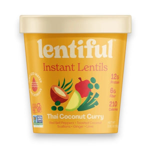 A yellow container of LENTIFUL - THAI COCONUT CURRY LENTILS is surrounded by fresh red bell pepper, lime halves, green onions, coconut flakes, and sliced chili on a green background, highlighting a spicy meal from LENTIFUL.