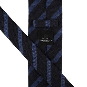 The AMANDA CHRISTENSEN Striped Jacquard Woven Silk Tie in Blue, featuring a black base with diagonal dark blue stripes, is showcased against a white background.