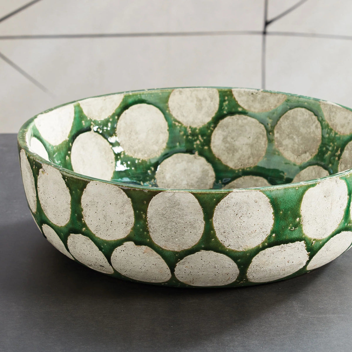 The NAPA HOME AND GARDEN KILEY BOWL IN GREEN is a round ceramic bowl with a glossy green base and bold silver circles on its surfaces, reflecting mid-century style. Shown here on a white background, it's perfect as a decorative fruit bowl.