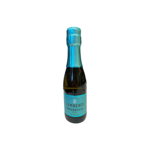 A mini bottle of LAMBERTI PROSECCO 187ML from Veneto, Italy, with a bright blue foil top and matching label, standing on a counter in a wine shop.