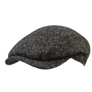 A close-up of the WIGENS Ivy Contemporary Donegal Tweed Cap in Dark Green highlights its authentic Donegal Tweed texture, featuring tiny flecks of red, yellow, blue, and purple woven throughout a richly mottled dark green background.