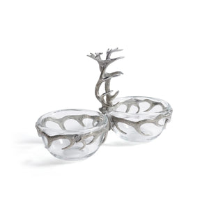 The ZODAX ST. ANTON Pewter and Glass Condiment Set features two bowls (3.5" and 5.25") linked by a silver antler-shaped handle, set on marble, with liquor bottles and glasses elegantly displayed in the background.