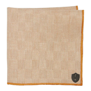 The CLIFTON WILSON - TAN CHECK LINEN POCKET SQUARE features a subtle check pattern, orange edging, and a small black shield emblem in one corner.