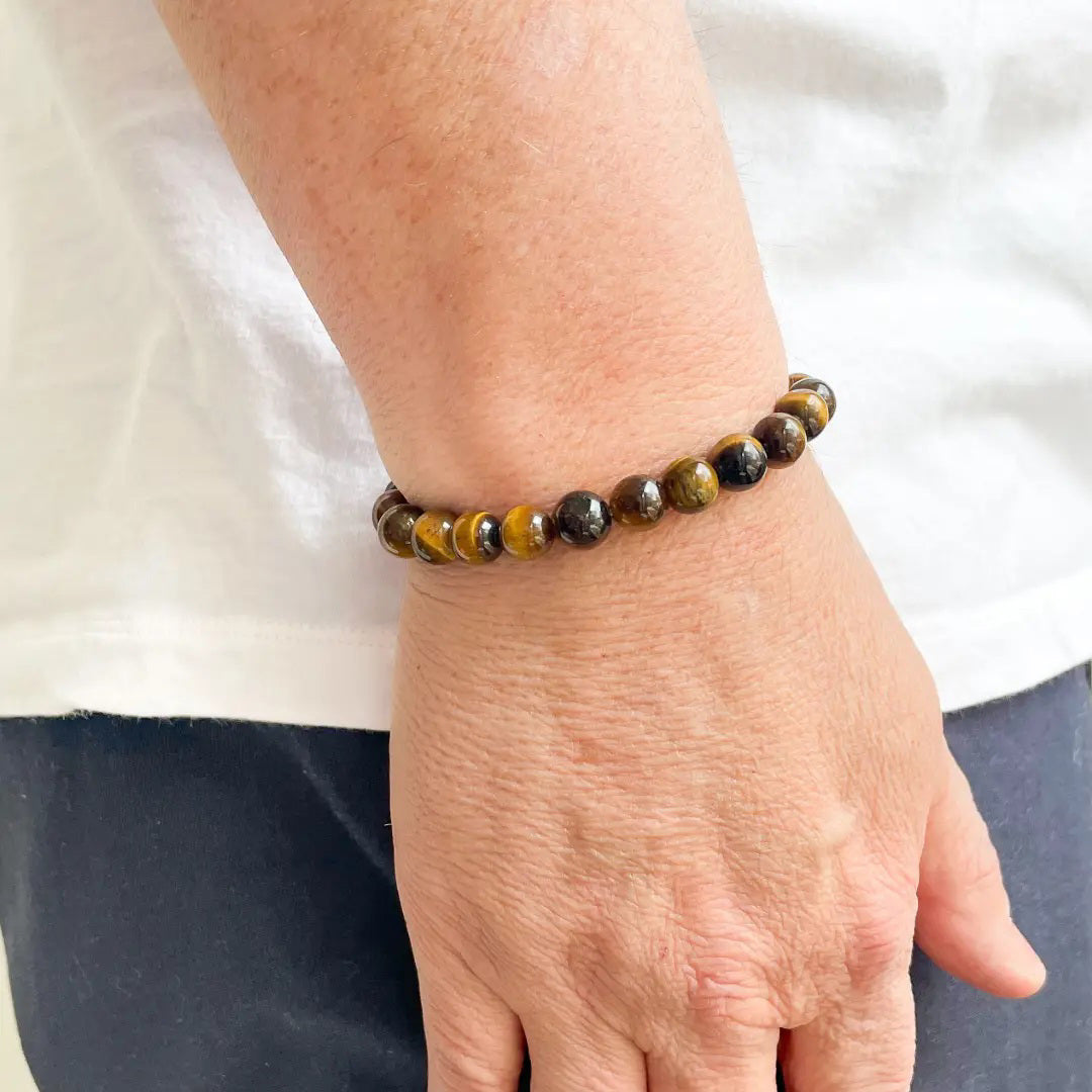 The STOLEN RICHES - MALLORCA TIGER EYE STONE BRACELET features polished round stones in brown and gold, arranged in a circular design to showcase grounding energy.