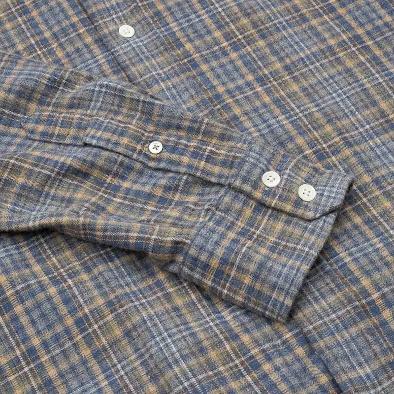 A close-up of the HARTFORD - PAUL Checked Flannel Shirt in Grey highlights the blue, brown, and grey plaid cotton fabric, with a focus on the cuff and sleeve featuring visible white buttons.