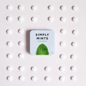 A small white tin labeled "SIMPLY GUM - PEPPERMINT MINTS" with a large image of a green peppermint leaf below the text. Experience a burst of freshness with these peppermint mints from SIMPLY GUM. The net weight is indicated as 1.1 oz (30g) in the bottom right corner.