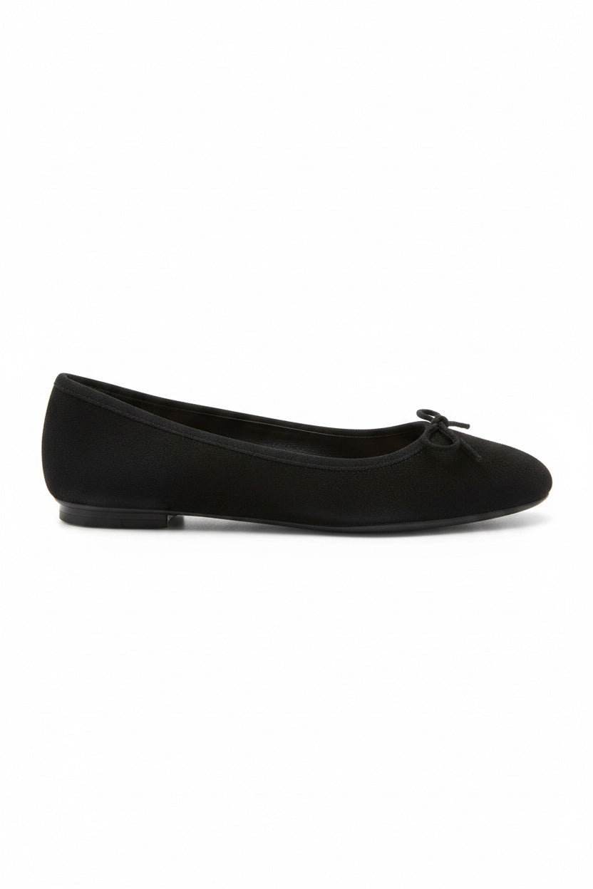 Wearing rolled-up blue jeans with REQINS - HARMONY SUEDE BALLERINA FLATS IN NOIR, featuring chic bow details—a timeless addition to any classic wardrobe.