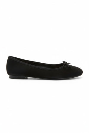 Wearing rolled-up blue jeans with REQINS - HARMONY SUEDE BALLERINA FLATS IN NOIR, featuring chic bow details—a timeless addition to any classic wardrobe.