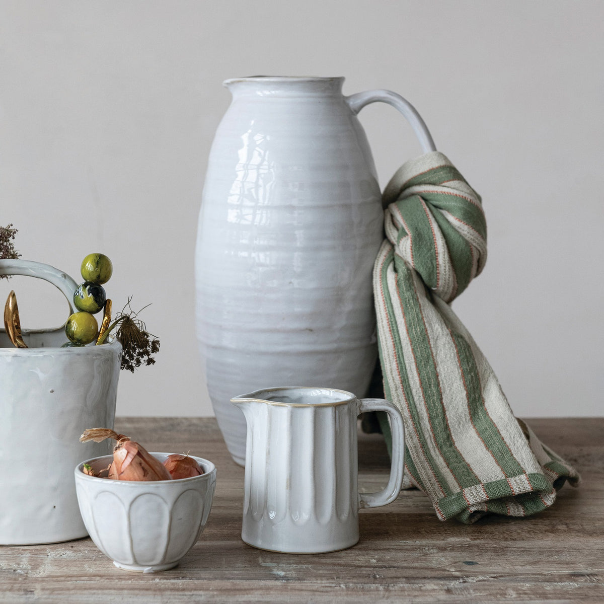 The WHITE STONEWARE PITCHER by CREATIVE COOP features a tall, oval shape, narrow neck, single curved handle, and a smooth light gray finish.