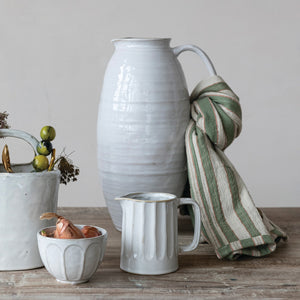 The WHITE STONEWARE PITCHER by CREATIVE COOP features a tall, oval shape, narrow neck, single curved handle, and a smooth light gray finish.