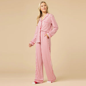 A woman wears the SOFTIES ARIA SLIM NOTCH COLLAR PJ SET, featuring a long-sleeved button-down top and matching wide-leg pants in red and white vertical stripes with red piping details.