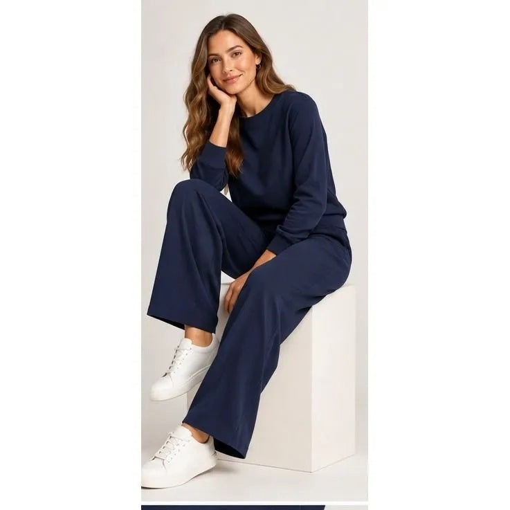 A woman wears a SOFTIES - DREAMTECH BOAT NECK WITH PINTUCK PANT SET in olive green, featuring a long-sleeve boat neck top and matching wide-leg pintuck pants.