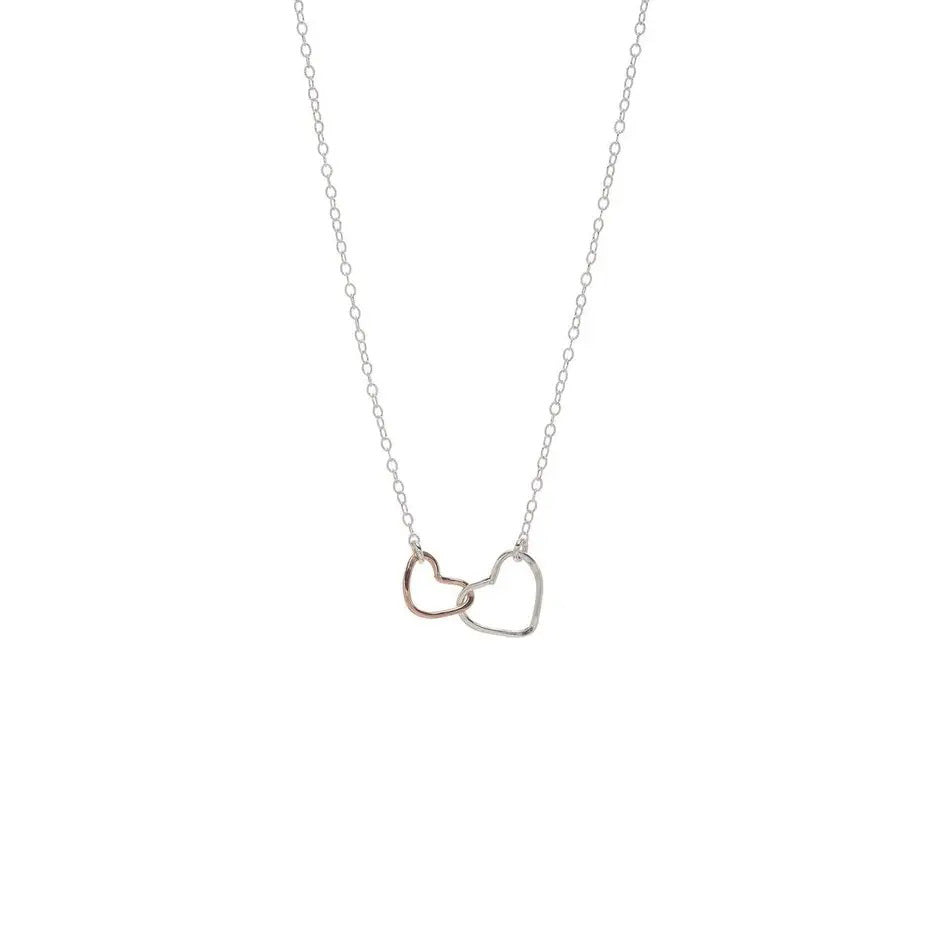 The KENDA KIST - INTERLOCKING HEARTS NECKLACE by KENDA KIST features a fine chain with interlocking sterling silver and rose gold-filled heart pendants.