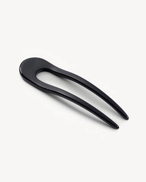 A smooth, black MACHETE - FRENCH HAIR PIN with two prongs, crafted from Italian acetate by MACHETE, rests on a plain white surface.