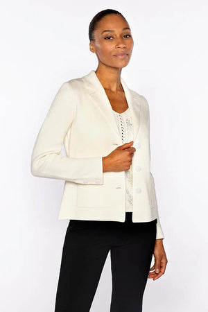 A woman stands confidently against a white background, wearing the KINROSS CASHMERE E-Fitted Notch Collar Cardigan in Cotton Sapphire over a white top and black pants. Her short hair is pulled back and she has a slight smile.
