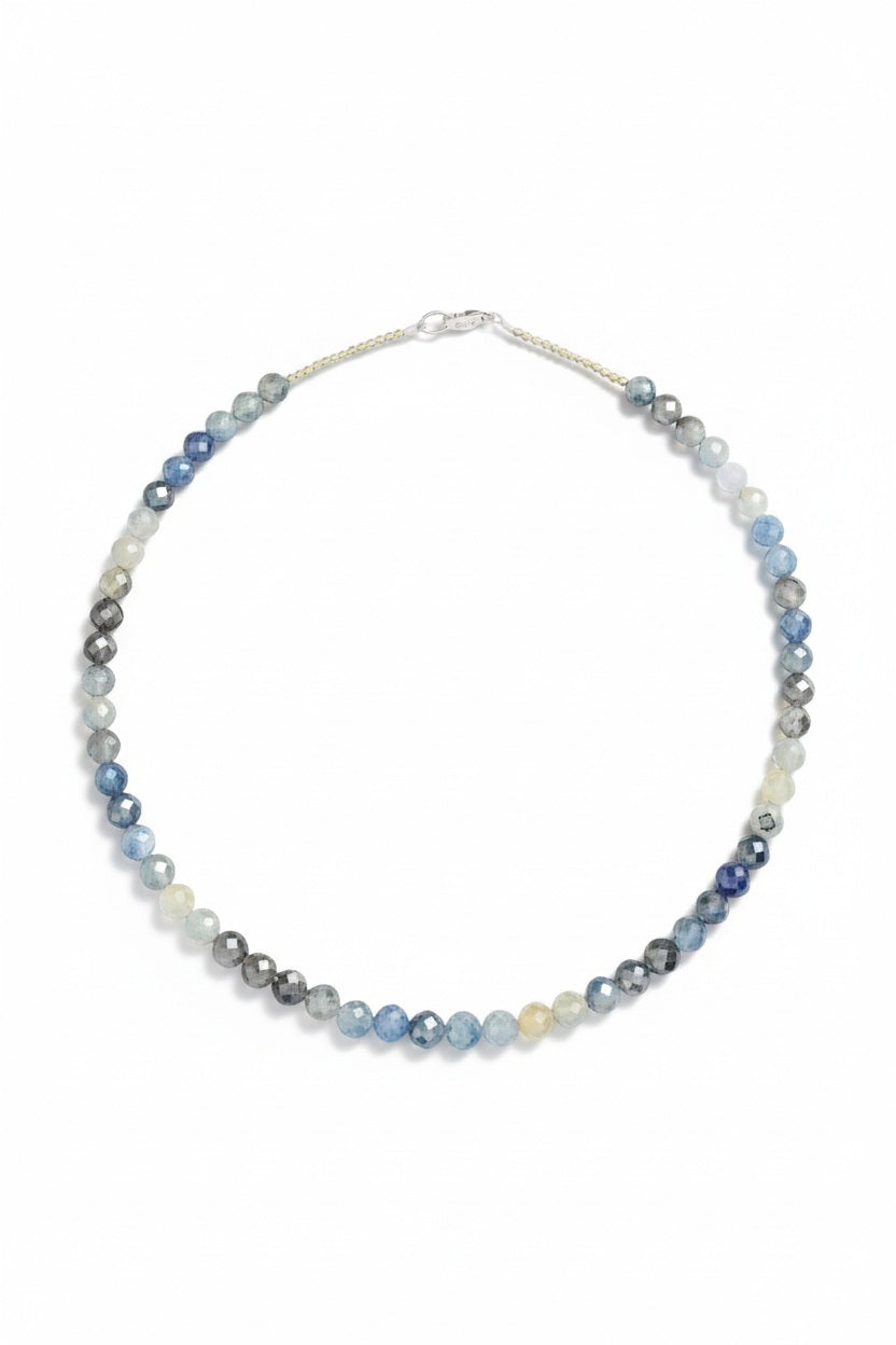 The ANN LIGHTFOOT Variegated Sapphire Ras Du Cou Necklace 18″ features round, faceted beads in shades of blue, gray, white, and yellow arranged in a subtle gradient and is secured with a silver lobster clasp.